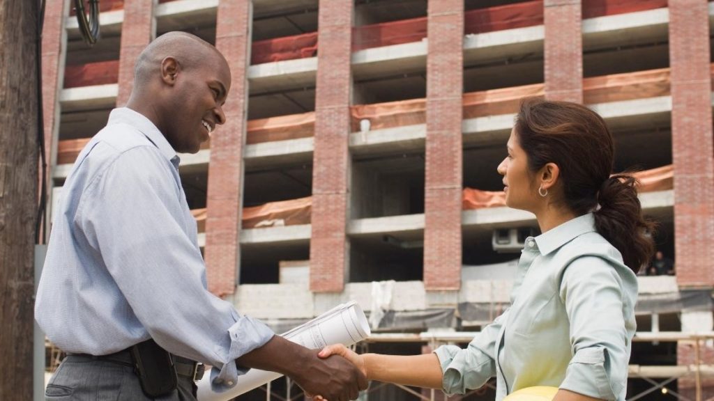 man and woman shaking hands at construction site
