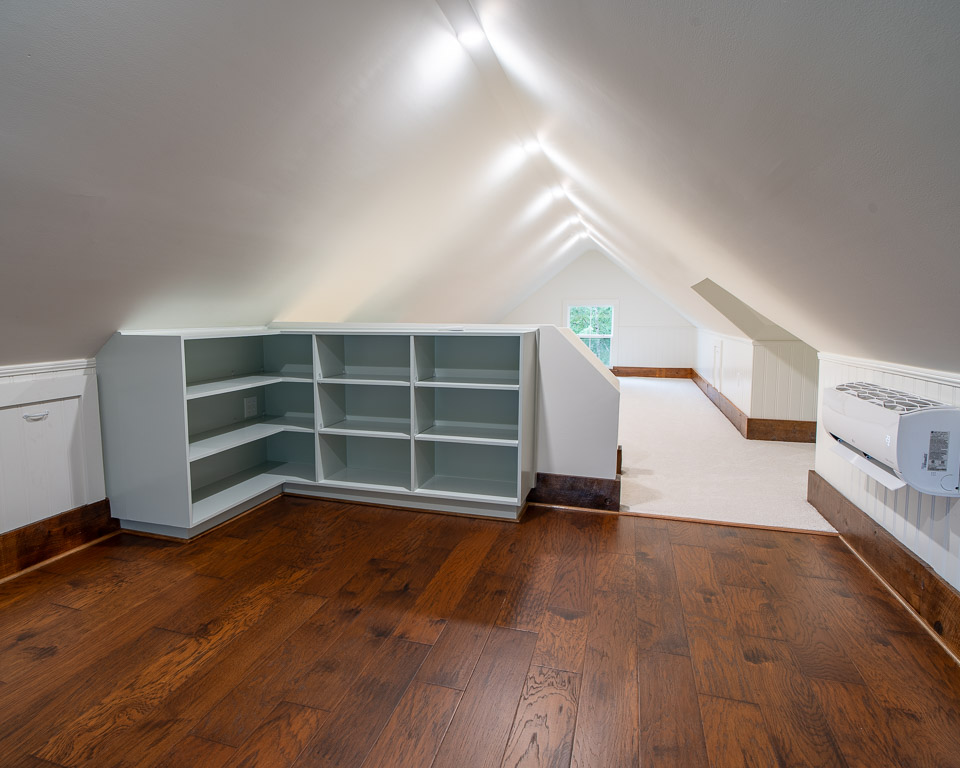 A newly remodeled attic with hardwood floors, shelving, and ceiling lights